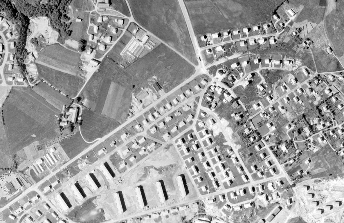 Svart-hvitt flyfoto av Nardo i 1964. Omkjøringsvegen er markert med rødt fra nede til venstre til et kryss øverst i bildet, der rundkjøringen over E6 ligger i dag. Njords veg og Røllikvegen er merket, og boligene ligger allerede tett langs vegen.